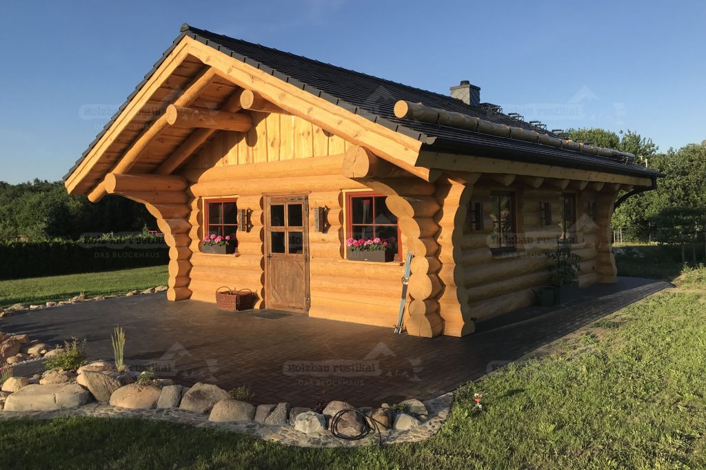 Frontansicht des Naturstamm-Gartenhauses Adler mit Holztür und Fensterläden