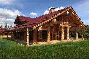 Seitenansicht des Naturstammhauses Lavanda mit überdachter Terrasse und massiven Holzstützen