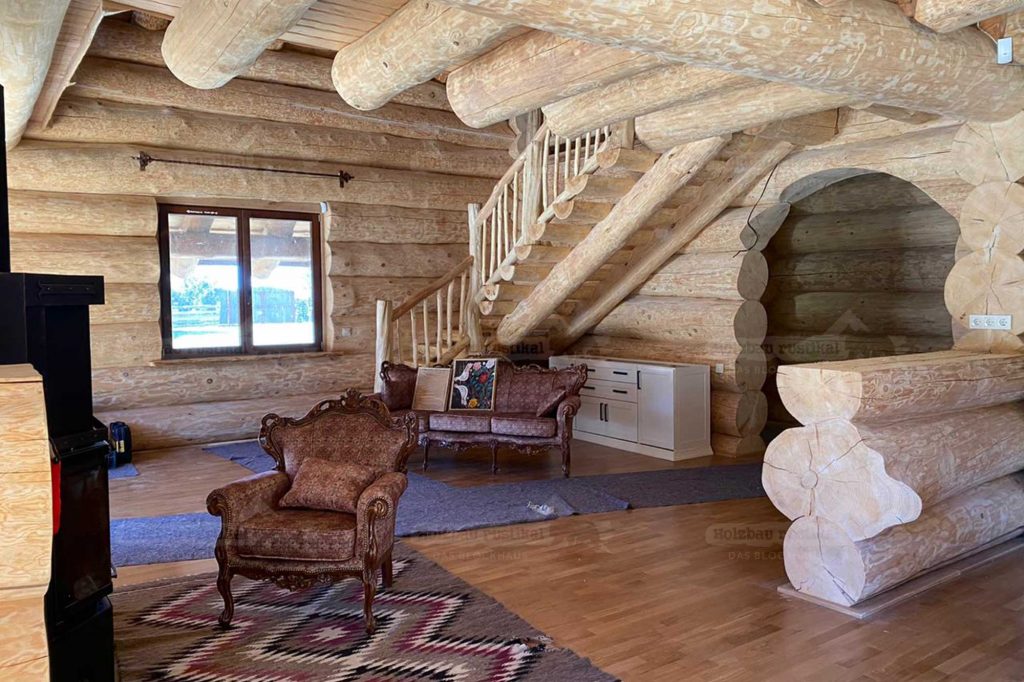 Wohnbereich im Naturstammhaus Lavanda mit massiver Holztreppe und rundem Durchgang und Möbeln