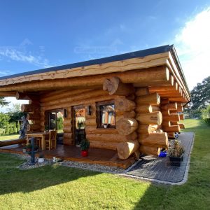Außenansicht eines Naturstammhauses Ostsee mit überdachter Terrasse