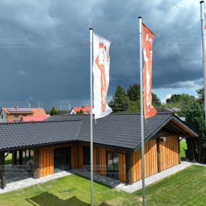 Vogelperspektive des Post-and-Beam Hauses Hamburg mit heller Putzfassade, Holzverkleidung, dunklem Ziegeldach und umliegender Grünfläche