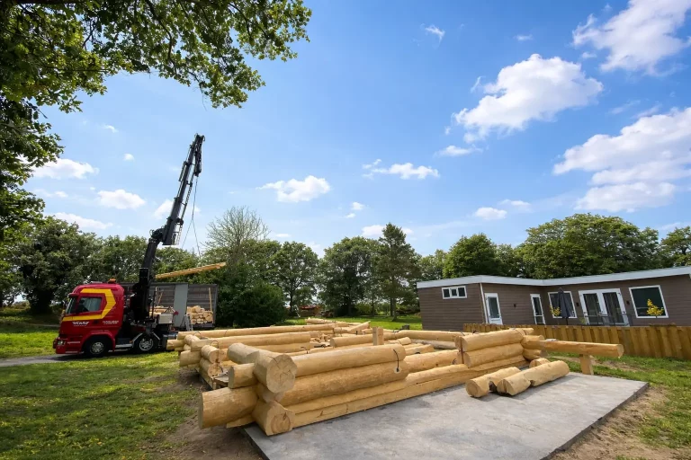 Blockhaus Ferienhaus Holland im Rohbau mit Kran bei der Anlieferung von Stammholz