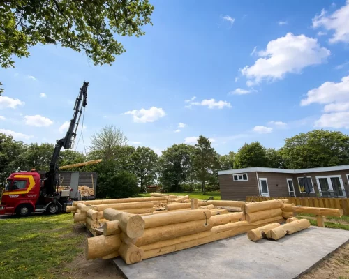 Blockhaus Ferienhaus Holland im Rohbau mit Kran bei der Anlieferung von Stammholz