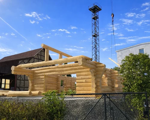 Naturstammhaus Lausitz NR3 im Rohbau während der Kranmontage beim Wandaufbau auf der Baustelle