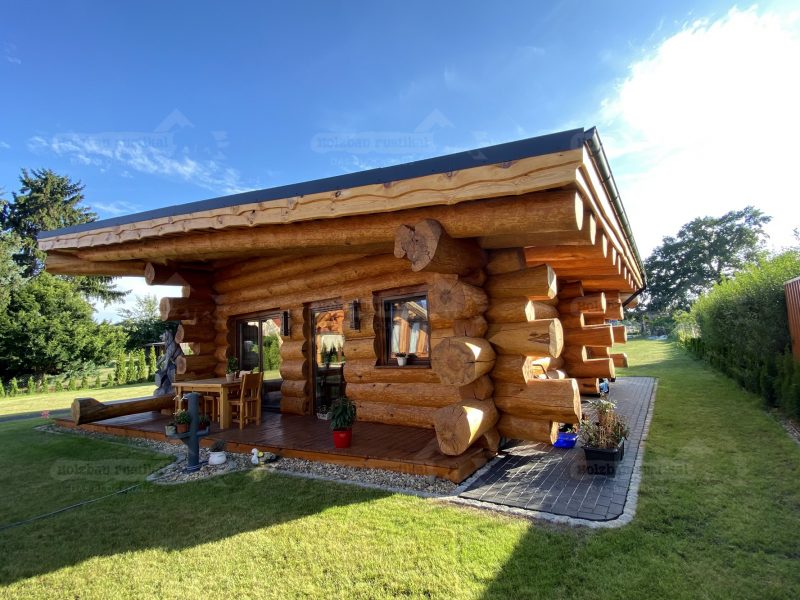 Außenansicht eines Naturstammhauses Ostsee mit überdachter Terrasse