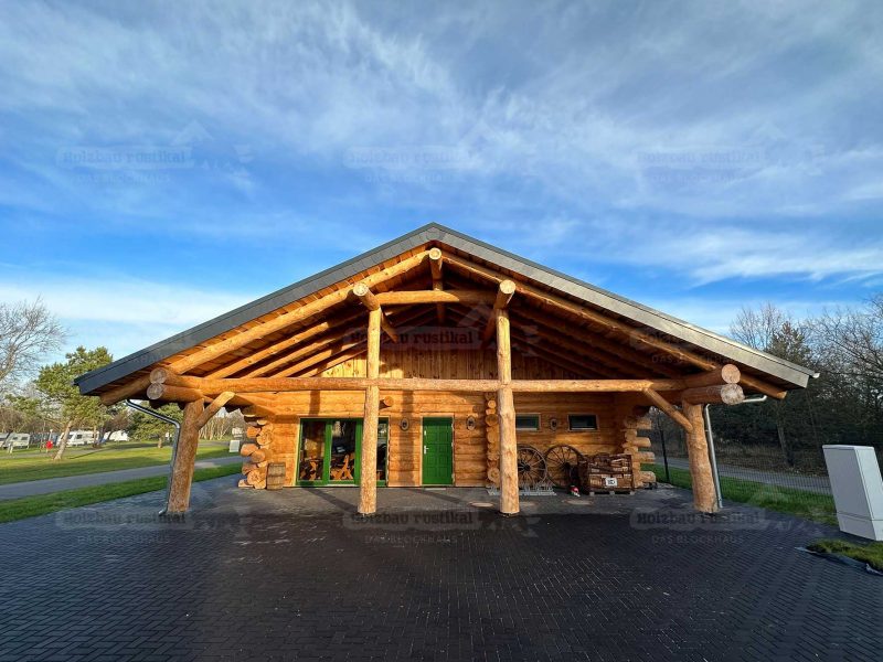 Vorderansicht vom Naturstammhaus See-Café aus Rundholz mit überdachtem Eingangsbereich