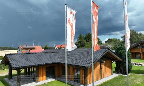 Vogelperspektive des Post-and-Beam Hauses Hamburg mit heller Putzfassade, Holzverkleidung, dunklem Ziegeldach und umliegender Grünfläche